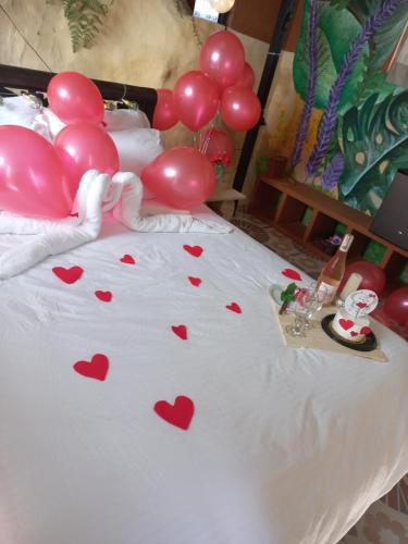 una cama con corazones rojos y globos en ella en El paraíso de Butulu, en La Vega