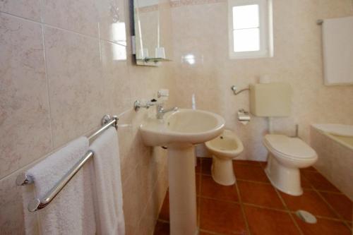 a white bathroom with a sink and a toilet at Apartamentos Os Descobrimentos in Burgau