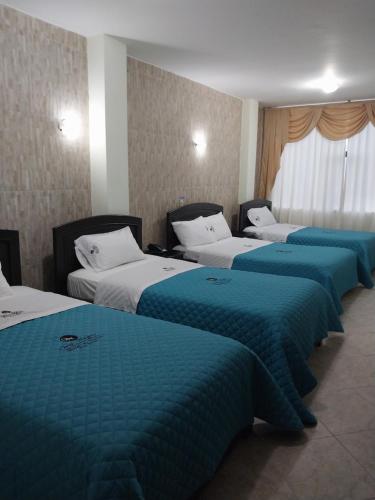 una fila de cuatro camas en una habitación de hotel en Hotel Oro Negro, en Puyo