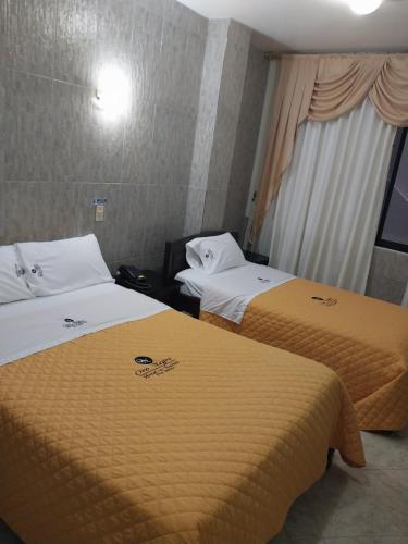 two beds sitting next to each other in a room at Hotel Oro Negro in Puyo