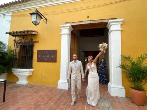 a bride and groom walking out of a yellow building at Karakali Boutique Hotel in Mompos