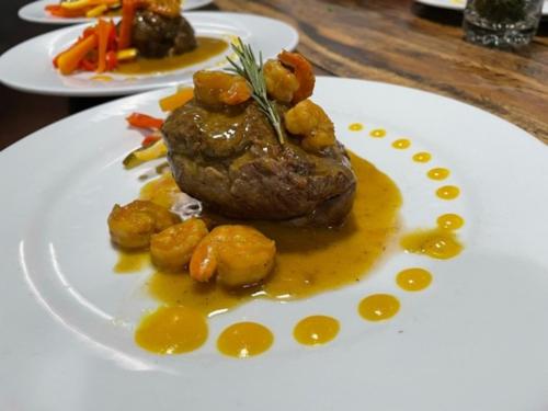 a plate of food with a piece of meat and potatoes at Karakali Boutique Hotel in Mompos