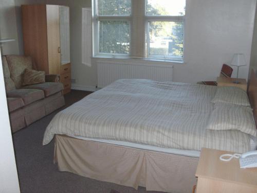 a bedroom with a bed and a chair and a window at Heritage Hotel in Narborough