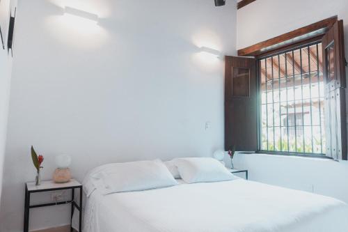 a white bedroom with a bed and a window at Karakali Boutique Hotel in Mompos