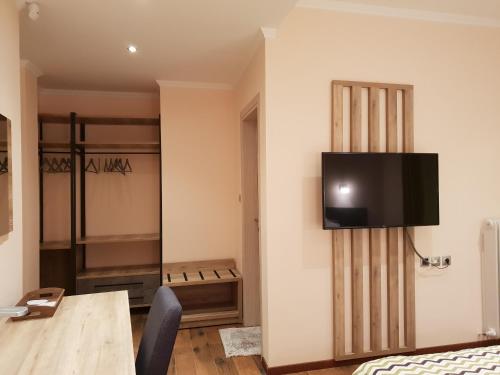 a room with a tv on the wall with a bed and a table at Mondeus Inn Luxury in Deskáti