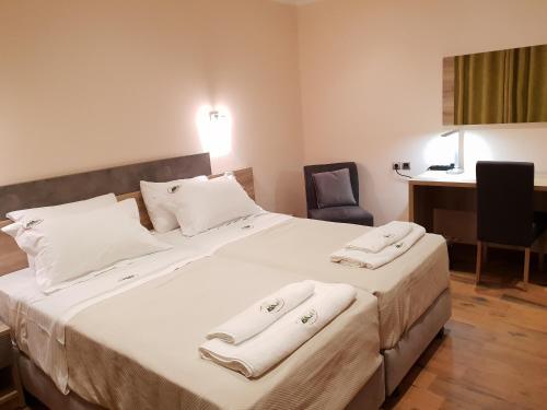 a bedroom with a large white bed with towels on it at Mondeus Inn Luxury in Deskáti