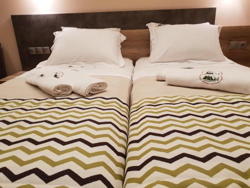 a bed with two pillows and towels on it at Mondeus Inn Luxury in Deskáti