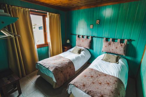 two beds in a room with green walls and a window at El Relincho in El Chalten