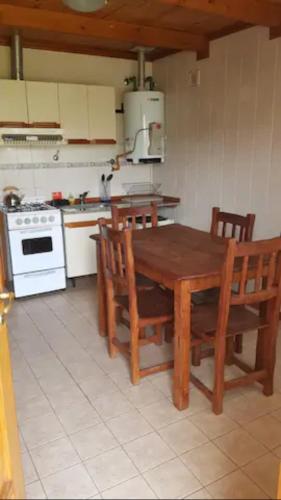 uma cozinha com uma mesa e cadeiras de madeira e um fogão em El Relincho em El Chaltén