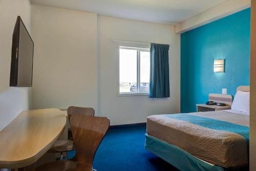 a hotel room with a bed and a table and a window at Motel 6-Grande Prairie, AB in Grande Prairie