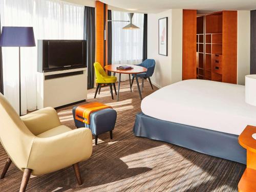 une chambre d'hôtel avec un lit, une table et des chaises dans l'établissement Sofitel Luxembourg Europe, à Luxembourg