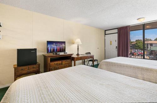 a hotel room with two beds and a flat screen tv at Candlewick Inn and Suites in Eureka Springs