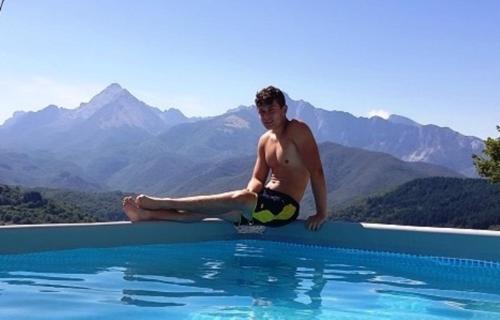 a man sitting on the edge of a swimming pool at DA ERCOLE casa vacanze di lusso con giardino, piscina e idromassaggio. in Vigneta