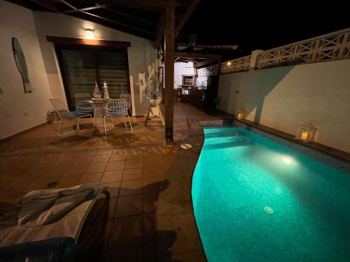 einen Pool in der Nacht mit einem Tisch und Stühlen in der Unterkunft Casa Mararía in Gran Tarajal