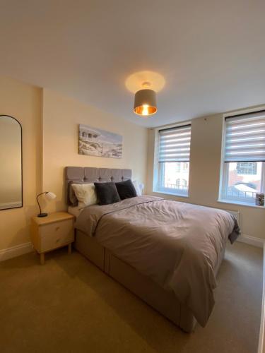 a bedroom with a large bed and two windows at 1 bedroom apartment in the heart of Bournemouth in Bournemouth