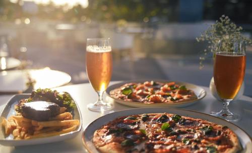 a table with two pizzas and two glasses of beer at Rhapsody Resort - Official in Gold Coast