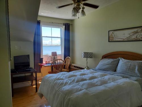 a bedroom with a bed and a desk and a window at Auberge Vue d'la Dune - Dune View Inn in Bouctouche