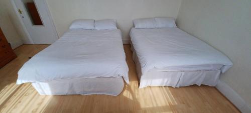 two beds in a small room with white sheets at Bruce Rooms in London