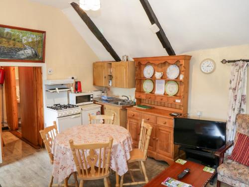 a kitchen with a table and chairs and a kitchen with a stove at The Thatched Cottage in Liscarney