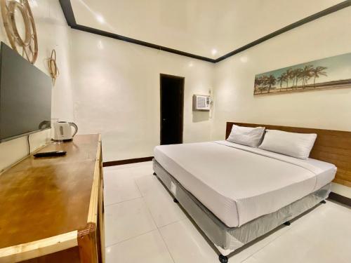 a bedroom with a large bed and a desk at Road Garden Villa in General Luna