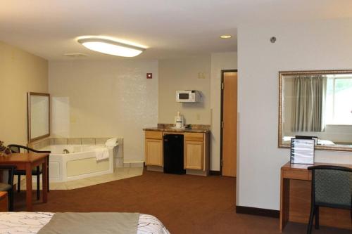 a room with a bed and a kitchen with a tub at Edmore Inn in Edmore