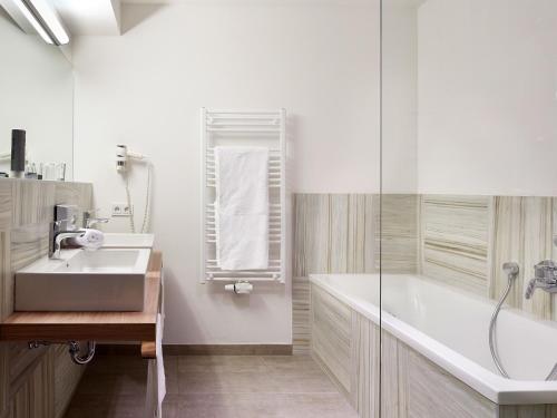 y baño con bañera, lavamanos y ducha. en Sonja Alpine Resort, en Piesendorf