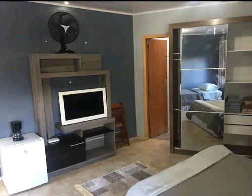 een woonkamer met een tv en een slaapkamer bij Suite/loft Jardim Botanico in Curitiba