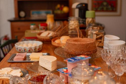 a wooden table with cheese and a cake on it at Pouso Jardim de Assis in Ouro Preto