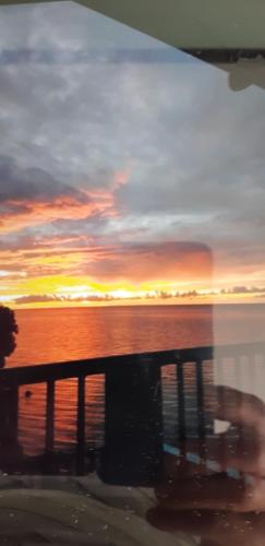 a person sitting on a pier watching the sunset at Sandra's holiday house in Oslob