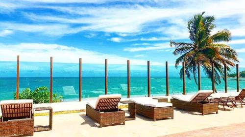 a patio with chairs and a view of the ocean at Flat Tabatinga Nord, vista para o mar in Conde