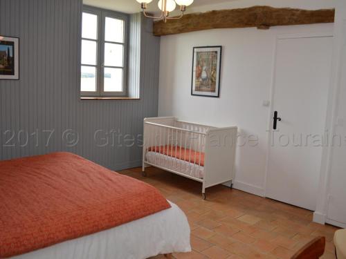 een slaapkamer met een wieg en een raam bij Gîte Parçay-sur-Vienne, 5 pièces, 8 personnes - FR-1-381-262 in Parçay-sur-Vienne