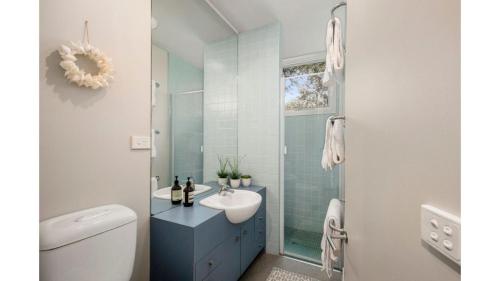 La salle de bains est pourvue d'un lavabo et d'une douche en verre. dans l'établissement Surf Sounds, à Inverloch