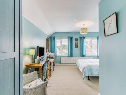 a bedroom with blue walls and a bed and a desk at Dunlin in Burnham on Sea