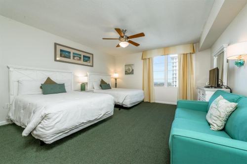 een slaapkamer met 2 bedden en een blauwe bank bij Unit 2430 Ocean Walk - 2 Bedroom Ocean View in Daytona Beach