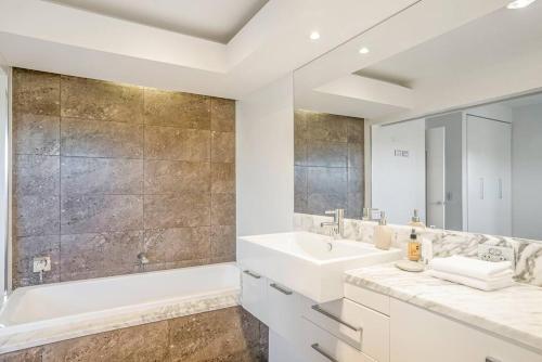 Un baño blanco con bañera y lavabo. en Fuller Holidays- Lot 7 - Byron Penthouse Apartment with Pool, en Byron Bay