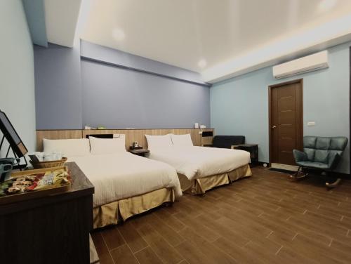 una habitación de hotel con 2 camas y una silla en 怡然自得-智能主題民宿 en Zhushan