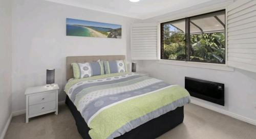 1 dormitorio con cama y ventana en Beachside Villa Ettalong Beach, en Ettalong Beach