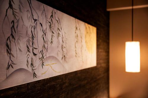 a painting hanging on a wall with a light at Rinn Shirakawa South in Kyoto