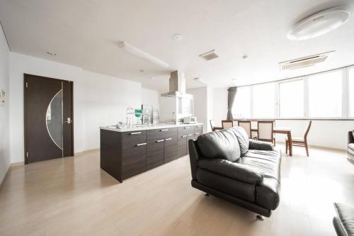 ein Wohnzimmer mit einem schwarzen Stuhl und eine Küche in der Unterkunft ROADSIDE House in Sapporo