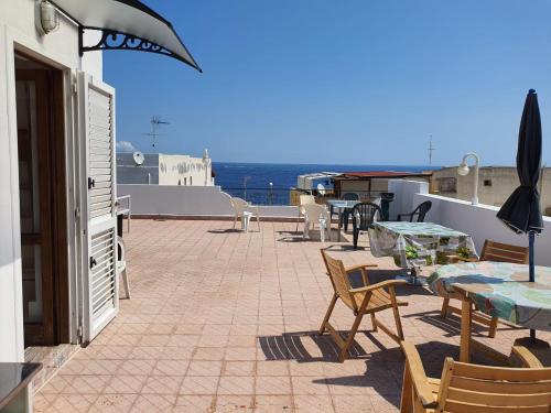 a patio with tables and chairs and the ocean at Case Vacanza Armando "Lipari" in Canneto