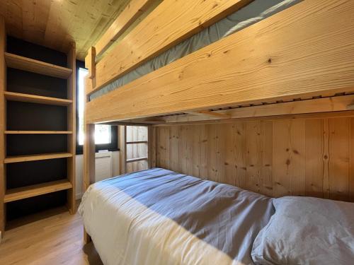 une chambre avec un lit dans une pièce en bois dans l'établissement Appartement rénové 3* avec balcon et Wifi, proche pistes, idéal famille - FR-1-598-110, aux Gets
