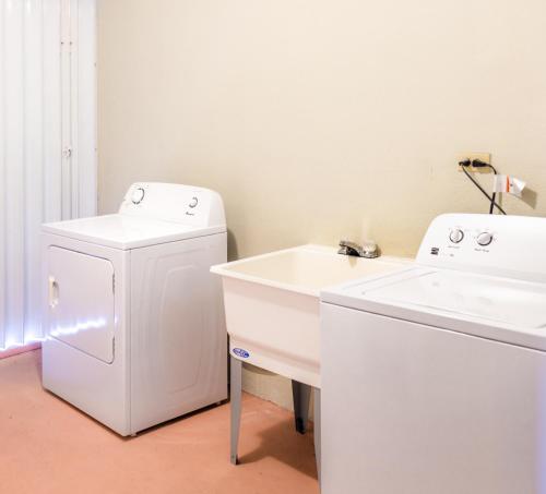 una lavanderia bianca con lavandino e lavatrice di Garden Villa Hotel a Tumon