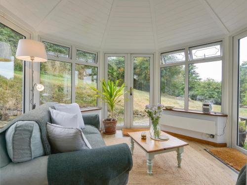 a living room with a couch and a table and windows at Kestorway in Gidleigh
