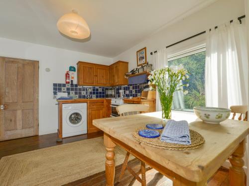a kitchen with a wooden table with a vase of flowers on it at Kestorway in Gidleigh