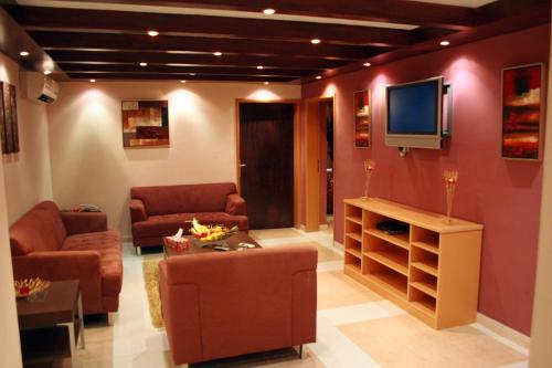 a living room with a couch and a tv on a wall at Mutrah Hotel in Muscat