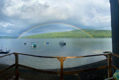 a rainbow over a lake with boats in the water at Brown's Beach at Schroon Lake in Schroon Lake