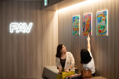 two women sitting on a bench looking at art on a wall at FAV HOTEL HAKODATE in Hakodate