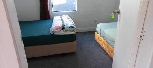 a small bedroom with a bed and a window at Central Holiday Home in Tauranga