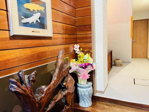 a vase with flowers in a hallway with wood paneling at 福宿 Fukuinn 101号室 in Takamatsu