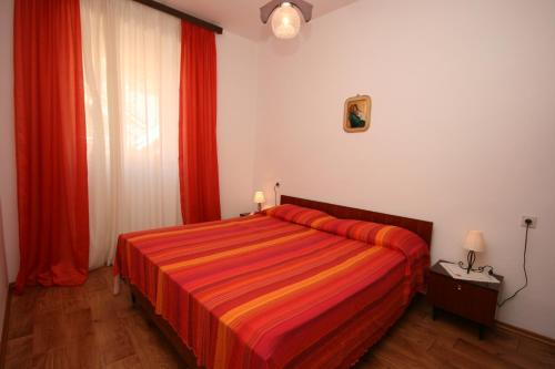 a bedroom with a large bed with red curtains at Apartments by the sea Zambratija, Umag - 7030 in Zambratija